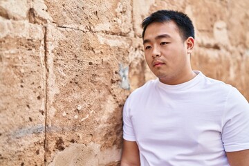 Young chinese man standing with relaxed expression at street