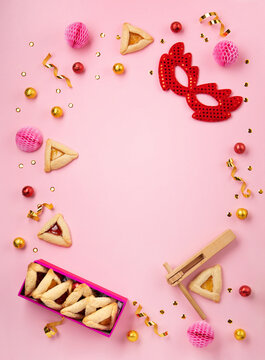 Hamantaschen Cookies, Red Carnival Mask, Noisemaker on Pink Background. Purim Celebration, Jewish Carnival Holiday Concept.