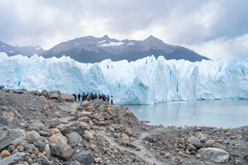 A lo lejos se ve un grupo de personas que se dirige caminando a recorrer el imponente glaciar Perito Moreno de Argentina.