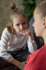 Two schoolgirl girls are sitting on the sofa in the living room and discuss misunderstandings, difficulties and family problems. Help and compassion concept