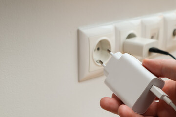 Man hands plugging the charger into an outlet in the wall, close-up. Hand turns on, turns off...