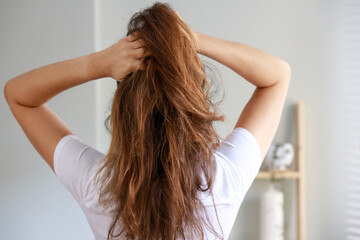 Young woman ruffling messy hair with hands in rear view shot