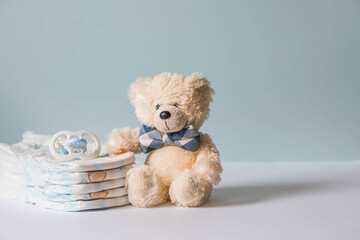 Wooden toys, a bear in a bow tie, a stack of diapers and baby supplies on the changing table. Space for text.