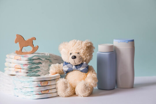 Wooden Toys, A Bear In A Bow Tie, A Stack Of Diapers, Bottles Without Labels And Baby Supplies On The Changing Table. Space For Text.