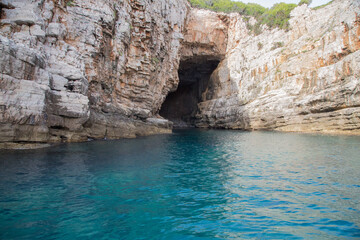 Landscape with pinewoods above limestone walls, scarps and a blue cave on Lokrum island in the Adriatic Sea with nits beautiful turquoise water near Dubrovnik, Croatia