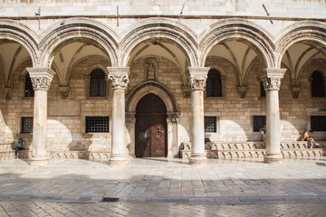 Fototapeta na wymiar The gothic Renaissance palace called Rector Palace - now a history museum - with its round arches in a main street made of limestone, Dubrovnik, Croatia