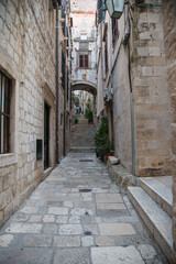Obraz premium Picturesque small alley with houses, stairway and pathway made of stone or limestone in the old town of Dubrovnik, Croatia