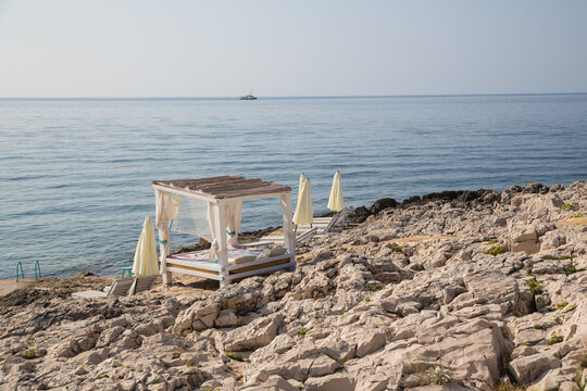 Relaxing at rocky Pachamama beach in a roofed sun bed with view to the Adriatic Sea - scenic coastal trail from Hvar town to village Milna on the island Hvar, Dalmatia, Croatia