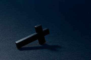 Black wooden traditional cross fallen down and lying on edge at an angle on the surface isolated on...