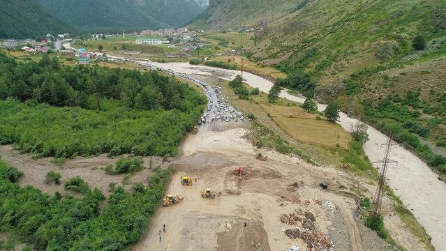Aerial of an excavator and wheeled bulldozers removing massive mudflow from the roadway. Natural disaster.