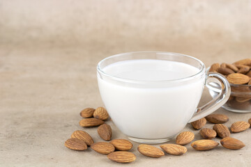 Almond milk in a glass cup and almond kernels on a light background. Copy Space. Selective focus.