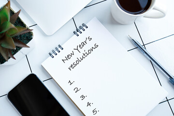 New years resolutions on notebook with notebook, cup of coffee and gadgets