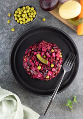 Traditional Russian salad - vinaigrette and cooking ingredients on a black background. Top view. Beet salad. Vegetarian food.