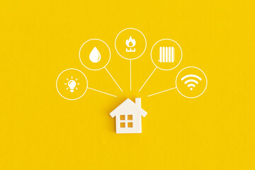 Miniature house and symbols of public utilities on a yellow background. Top view. Flat lay.