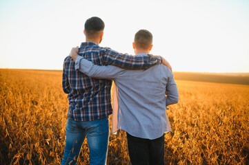 Two young men hugging against the backdrop of the sunset, looking forward to the horizon.