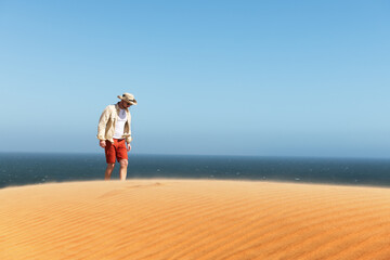 Single man in a cowboy hat in the Namib desert on Atlantic ocean background. Travel concept