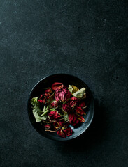 Obraz na płótnie Canvas Dried red roses in a black ceramic bowl. Copy space