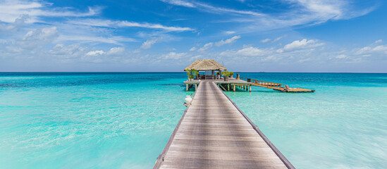 Tranquil Maldives island, luxury over water villas resort and wooden pier. Beautiful sunny sky. Sea bay lagoon beach background. Summer vacation holiday. Paradise shore exotic landscape, pristine blue