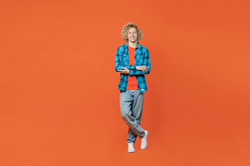 Fototapeta na wymiar Full body smiling happy confident young blond fun man wear blue shirt orange t-shirt look camera hold hands crossed folded isolated on plain red background studio portrait. People lifestyle concept.