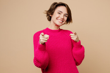 Young confident leader smiling woman wear pink sweater point index finger camera on you motivating encourage isolated on plain pastel light beige background studio portrait. People lifestyle concept.
