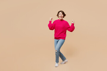 Full body young overjoyed happy fun cool woman wear pink sweater walk go do winner gesture say yes...