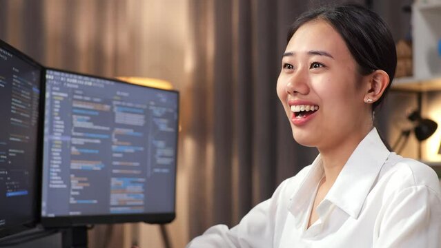 Close Up Of Asian Woman Programmer Smiling To Camera While Creating Software Engineer Developing App, Program, Video Game On Desktop Computer At Home. Terminal With Coding Language 
