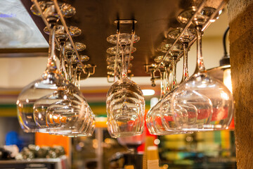 Fototapeta na wymiar Hanging brandy glasses on a rack above liquor counter with selective focus on the middle row glass 