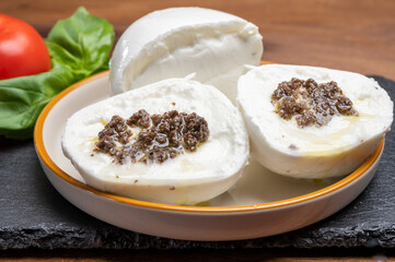White balls of Italian soft cheese Mozzarella di Bufala Campana stuffed with black truffles mushrooms