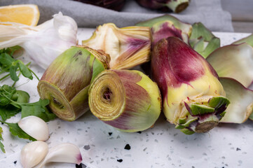 Heads of raw fresh purple romanesco artichoke vegetable and pilled hearts