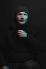 Lifestyle concept. Man with winter hat and black coat studio portrait. Model with beard looking at camera with serious look. Red and blue color split effect style. 3D glitch virtual reality effect