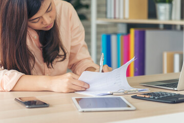 Asian Female freelance using laptop at home office desk. Woman reading financial graph chart Planning analyzing marketing data. Asian female people working office firm with business stuff, coffee cup