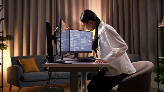 Asian Woman Programmer Walking Into The Working Space Before Sitting To Creating Software Engineer Developing App, Program, Video Game On Desktop Computer At Home
