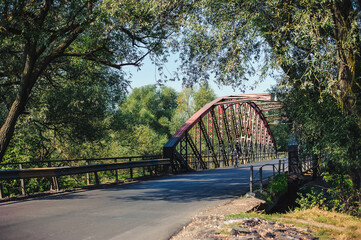 A cyclist rides through the old iron bridge among the trees