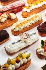 An assortment of vibrant eclair flavors. Honey caviar - molecular cuisine. Pavlova, coffee, berry, caramel, mango, nuts. French dessert with delicate cream. Eclairs on a white background.