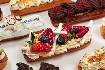Elegant éclairs dressed with whipped cream and a colorful array of fresh fruit, presenting a tempting treat for dessert connoisseurs.