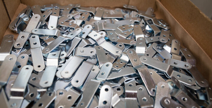 Stamping plates of complex shape ready for assembly part, made of steel on CNC machines, presses. Automotive part after stamping process. Galvanized steel parts – manufacturing process. Steel elements