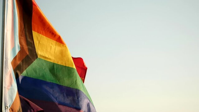 LGBT Pride Flag Waving. New LGBT pride flag is symbol LGBT, Gay, Lesbian, Peace, Pride, LGBTQ, Bisexual, Homosexual, Transgender, Love. Rainbow flag waving on sunset, soft focus. Slow motion