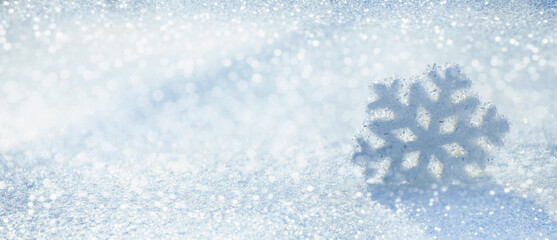 Christmas winter background, banner - view of a decorative snowflake on snow sparkling in the rays of the sun, selective focus, copy space for text