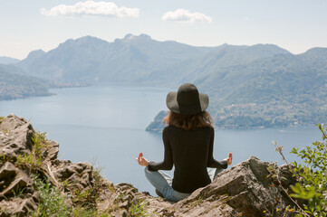 Fototapeta na wymiar Frau beim Meditieren in der Natur auf einem Berg mit Seeblick und Bergblick