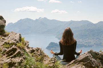 Naklejka na ściany i meble Junge Frau beim Meditieren mit Aussicht auf den Comer See und Berge
