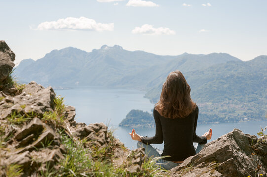 Junge Frau beim Meditieren mit Aussicht auf den Comer See und Berge