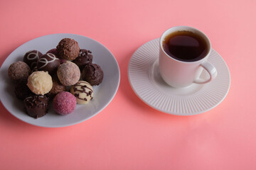 photo of a cup with a drink and chocolates next to it on a pink background