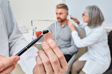 Hearing aid specialist doing ear examination and recommended Completely-in-Canal hearing aid to...
