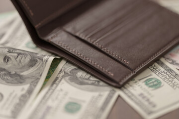 Full grain leather wallet with currency on walnut table