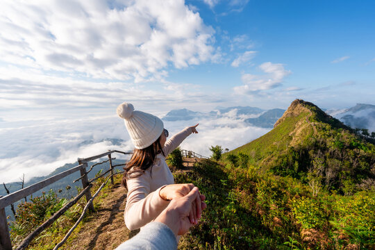 Young couple travelers looking at the sunrise and the sea of mist at Phu Chi Dao, Chiang Rai