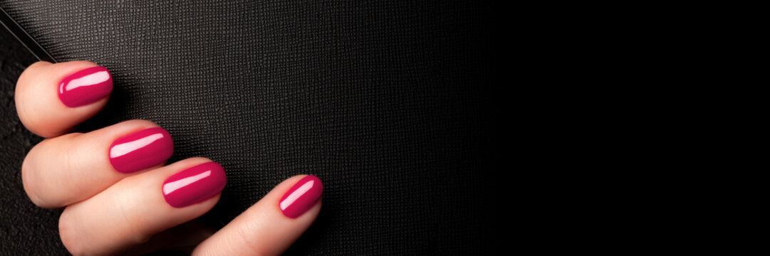 Female hand with beautiful manicure - viva magenta, pink nails on black leather surface background banner with copy space. Wide panoramic header