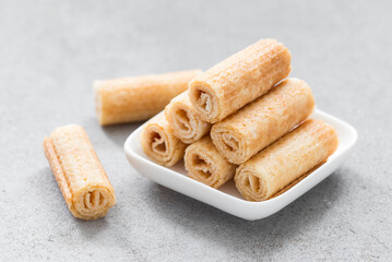 Fototapeta na wymiar Sweet waffle rolls on a plate. Light grey background