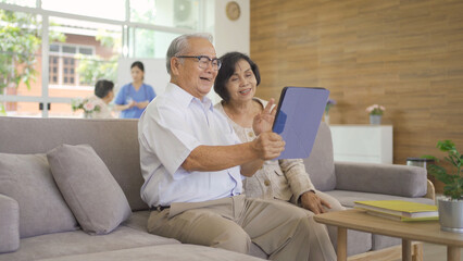 Portrait of happy smiling Asian old couple senior elderly patient using technology tablet device, woman person in hospital in medical healthcare concept. People lifestyle. Family wife and husband
