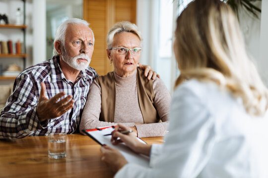 Worried mature couple talking to their doctor during her home visit