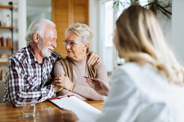 Mature couple talking to their doctor during her home visit